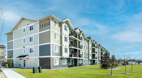 A large apartment building with green space in front