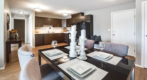 A kitchen with dark cabinets, black appliances and a rectangular kitchen table