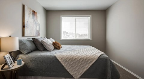 A bedroom with a bed, a nightstand, and a window.