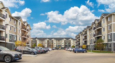 A large apartment complex with parking in between the buildings