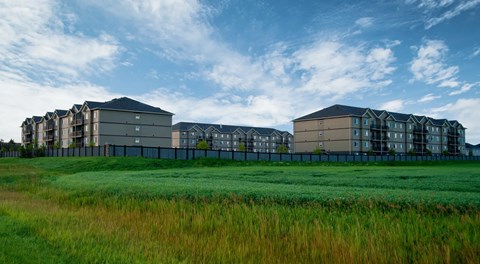 A large apartment complex with a grassy field next to it