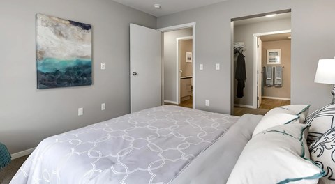 A bedroom with a queen sized bed with an entrance to a walk in closet and ensuite