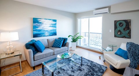 A living room with a grey couch, a coffee table and chair set next to a glass sliding door