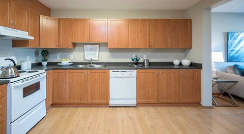 A large open kitchen with lots of wooden cabinets and white appliances