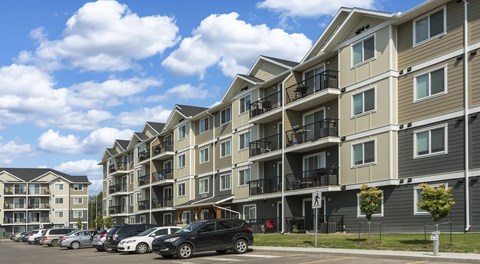 An apartment complex with cars parked in front.
