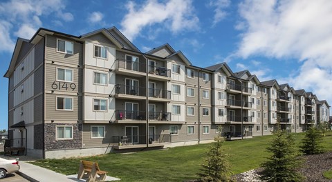 A four storey apartment building with a green space in front