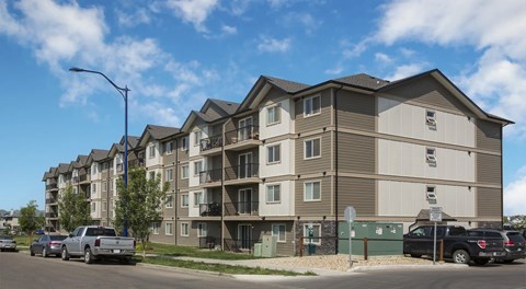A apartment building with cars parked in front.