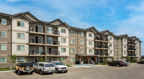 Apartment complex with cars parked in front.