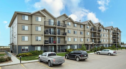 Apartment building with cars parked in front.