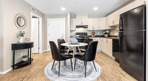 A kitchen with light cabinets and black appliances, a round table sits in the centre