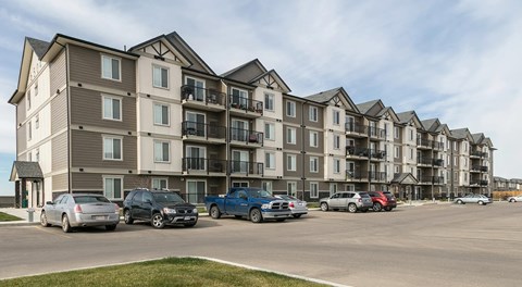 A large apartment building with lots of parking out front