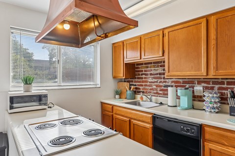 A kitchen with a white stove top and wooden cabinets.