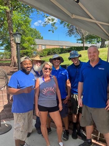 A group of five people wearing blue shirts are standing under a white canopy.