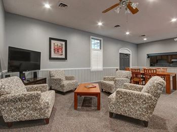 A living room with a television, chairs, and a coffee table.