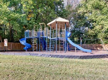 A playground with a blue slide and a brown roof.