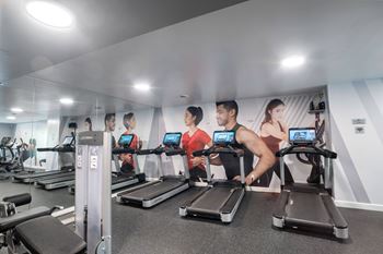 A gym with people exercising on treadmills.