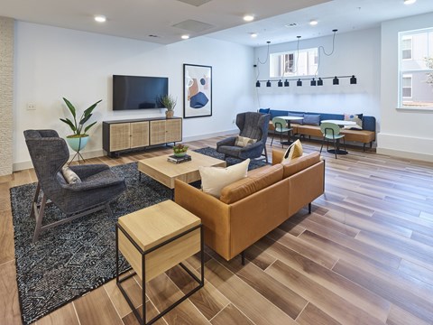 A living room with a brown couch, a black chair, and a TV on the wall.