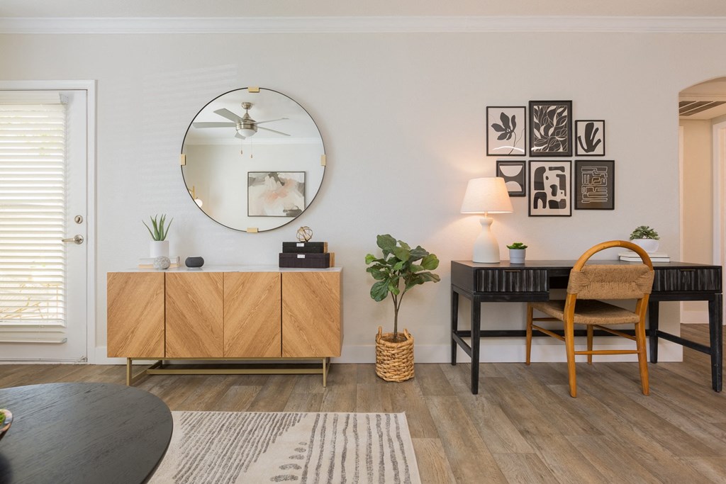 a living room with a mirror and a desk with a chair