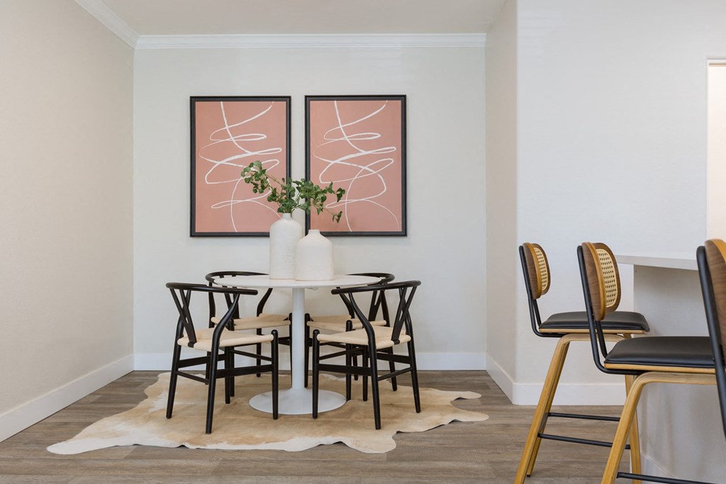 a dining room with a table and chairs and two paintings on the wall
