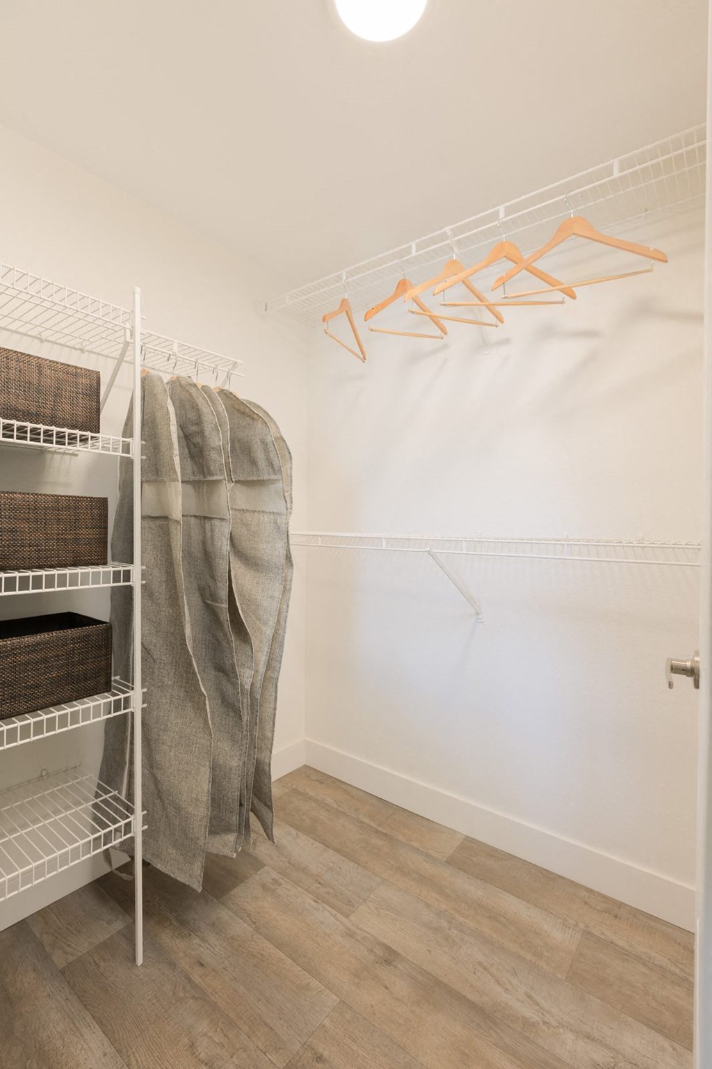 a closet in a room with white walls and wood flooring