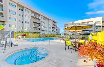 A swimming pool area with a yellow umbrella and chairs.