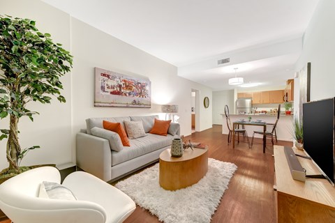 A living room with a white chair, a grey couch, a coffee table, and a painting on the wall.