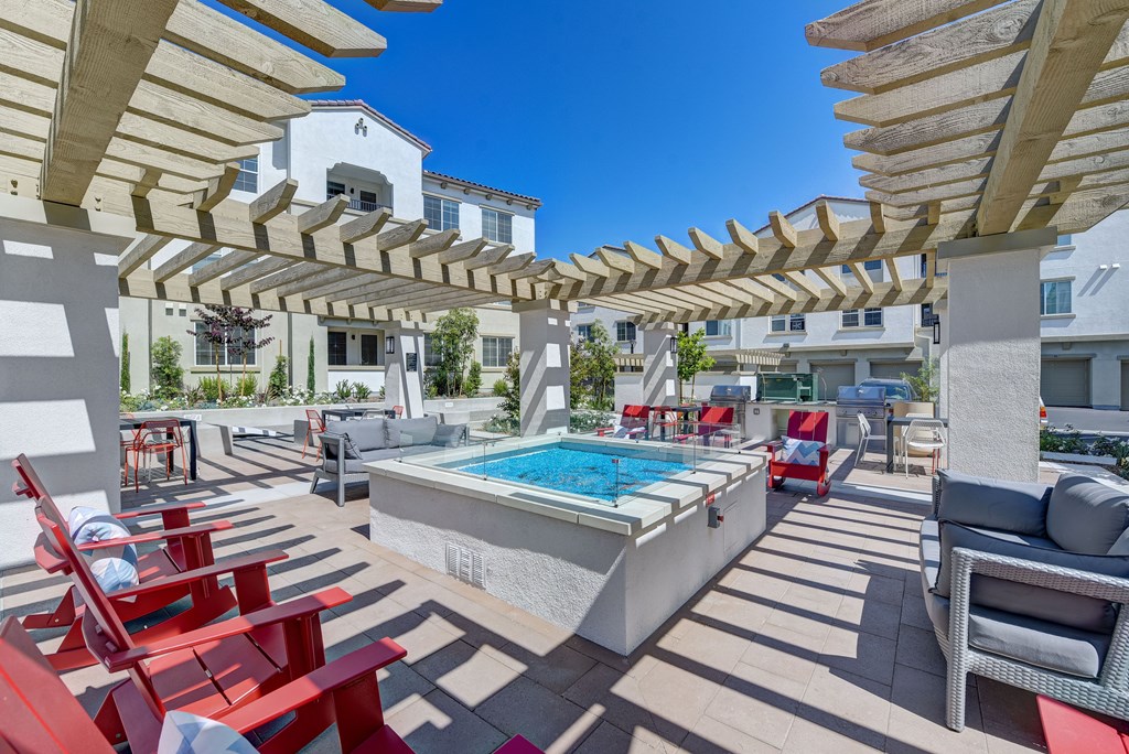 A pool surrounded by red chairs and wooden pergolas.