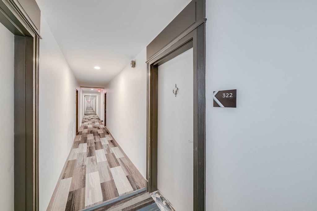 a corridor with a wood floor and a door to a hotel room