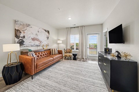 A living room with a brown leather couch, a black cabinet, and a large abstract painting on the wall.