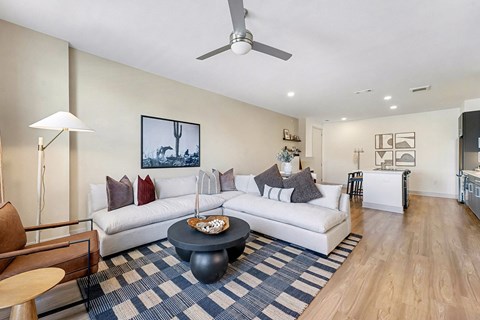 A living room with a white couch and a blue and white rug.