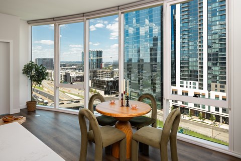 A dining room with a table and chairs and a view of the city.