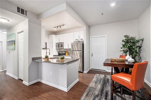 A kitchen with a bar area and a dining table with chairs.