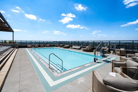A swimming pool on a rooftop with a chair and a table.