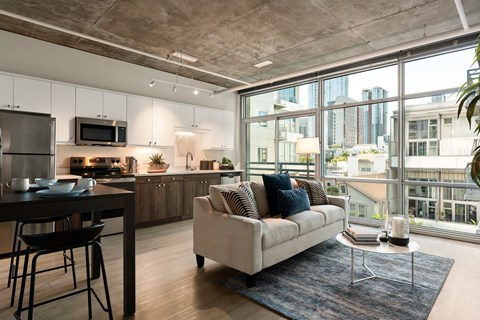 A modern kitchen with a dining table and a couch with a view of the city.