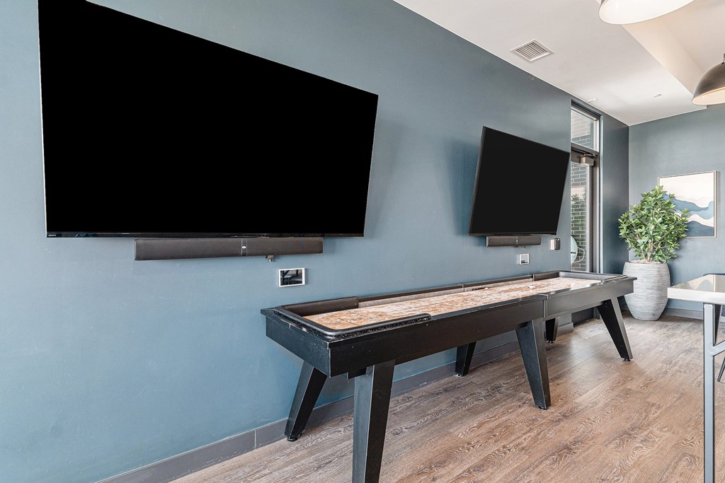 A black air hockey table is in the middle of a room with a blue wall.