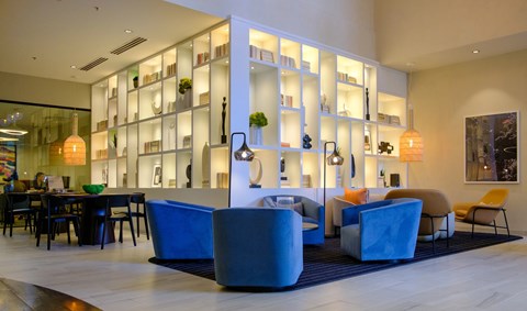 A modern living room with a blue sofa and a white bookshelf.