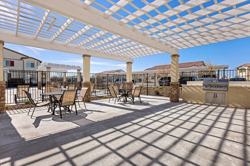 a patio with tables and chairs under a white pergola