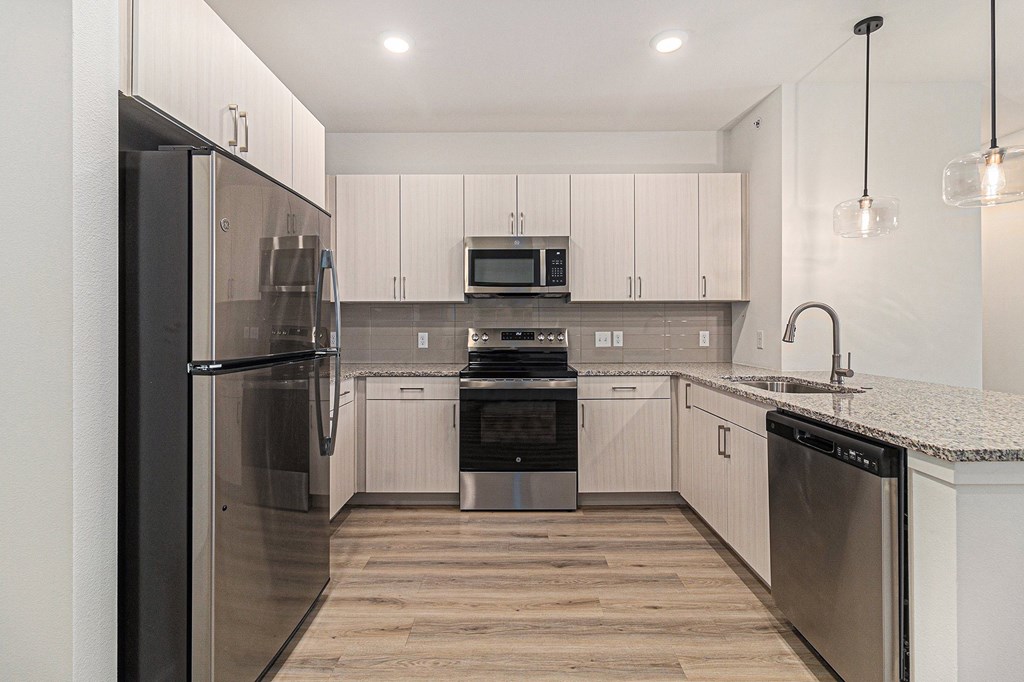 A modern kitchen with stainless steel appliances and wooden flooring.