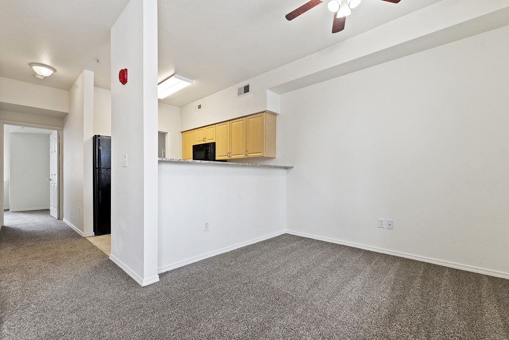 A room with a ceiling fan and a kitchenette.