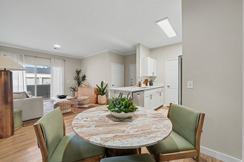 A dining room with a round table and green chairs.