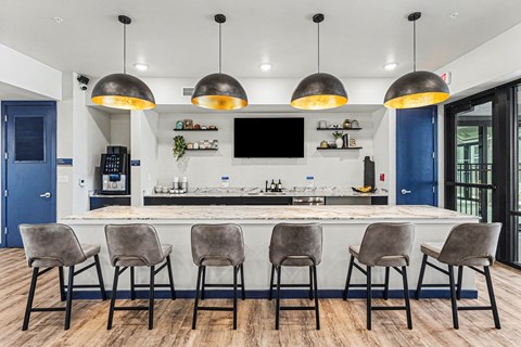 A modern kitchen with a bar area and grey chairs.