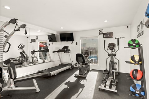 A gym with a variety of equipment including treadmills, weights, and exercise balls.