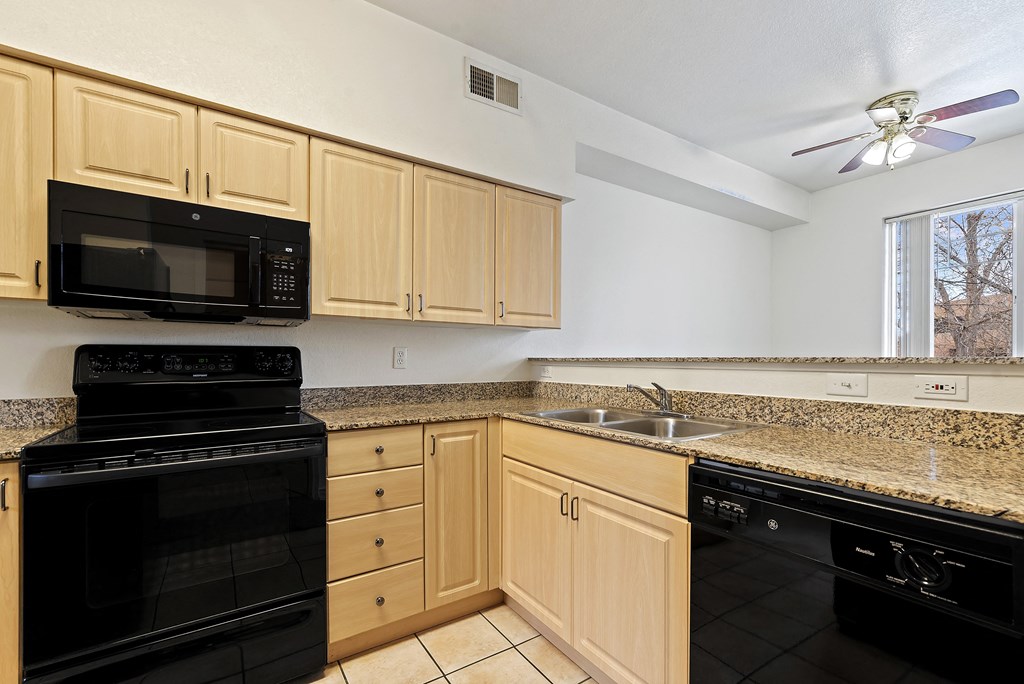 A kitchen with black appliances and wooden cabinets.