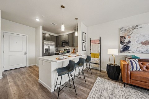 A kitchen with a white island and black chairs.