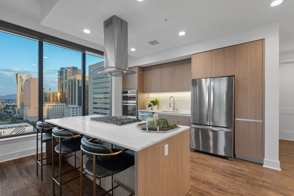 a kitchen with wooden cabinetry and a large island with a marble countertop at Stanza Little Italy, California, 92101