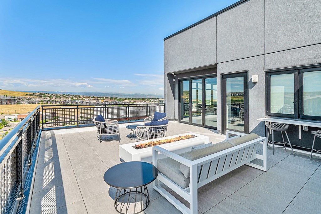 A balcony with a table and chairs overlooking a cityscape.