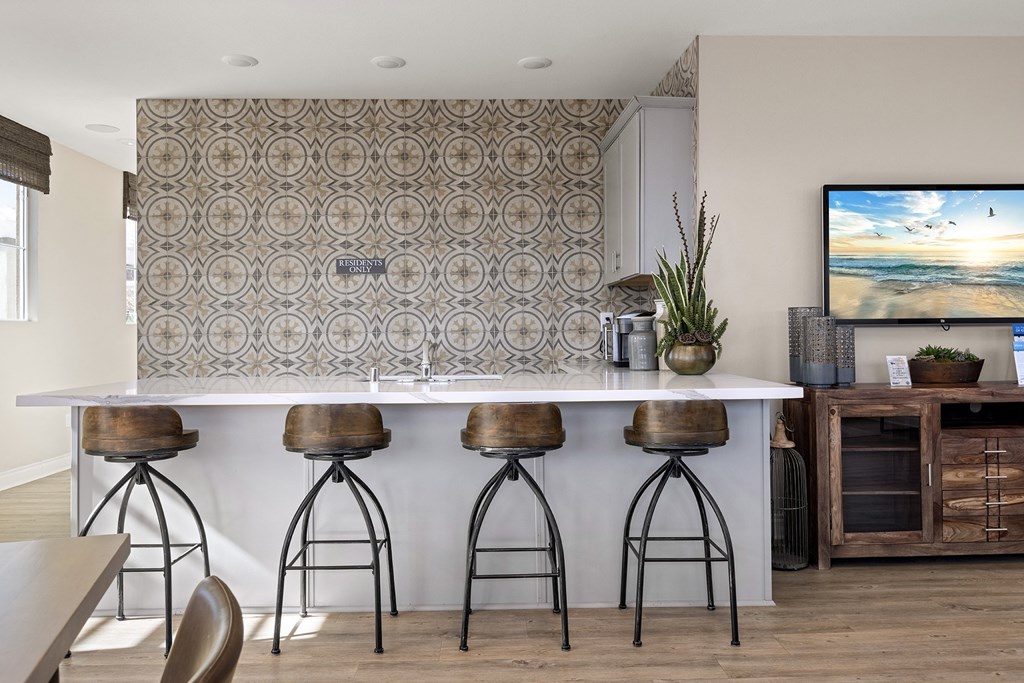 a kitchen with bar stools in front of a counter and a tv
