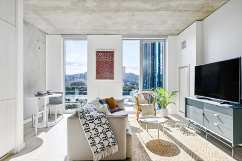 a living room with white walls and a large window with a view of a city