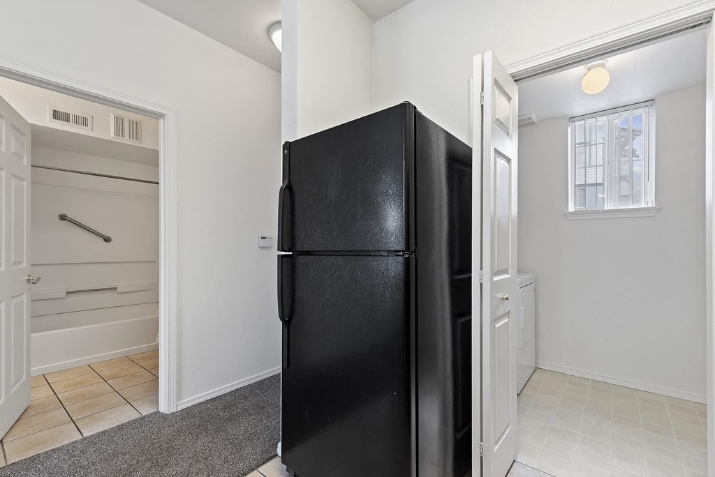A black fridge in a room with white walls.