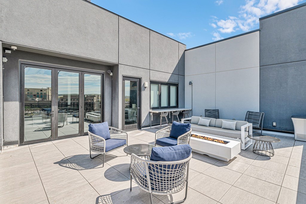 A patio with a white couch and blue chairs.